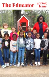 President Erica Jones stands outside with smiling students with a Free Little Library. 